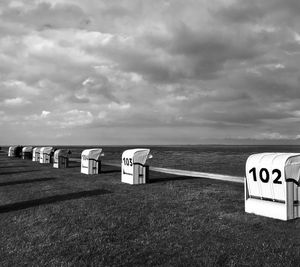 Hooded beach chairs on shore against sky