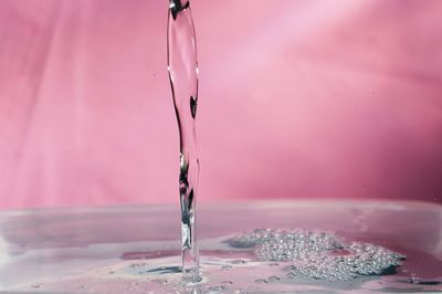 Close-up of water splashing on recipient against wall