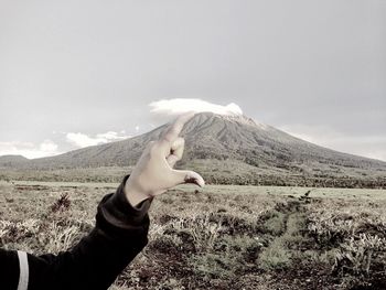 Optical illusion of woman hand holding mountain against sky
