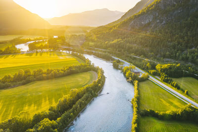 Scenic view of agricultural field by river against sky