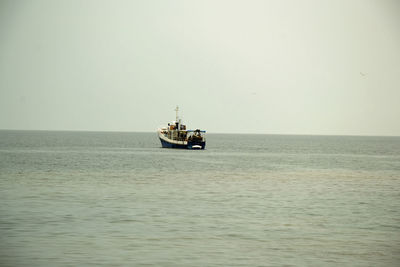 Boat sailing in sea against clear sky