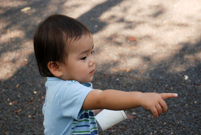 High angle view of boy pointing while standing on footpath