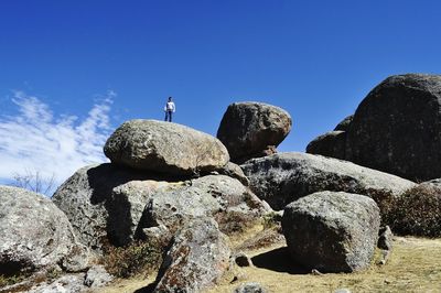 Low angle view of man standing on boulder