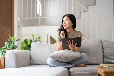 Young woman using phone while sitting at home