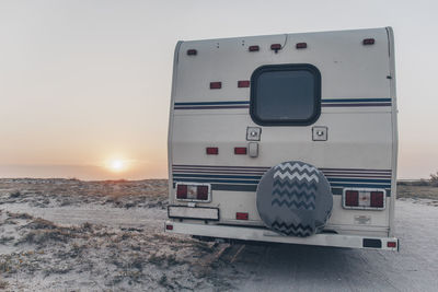 The back of the trailer, which stands on the sandy curb against the horizon and sunset on the coast