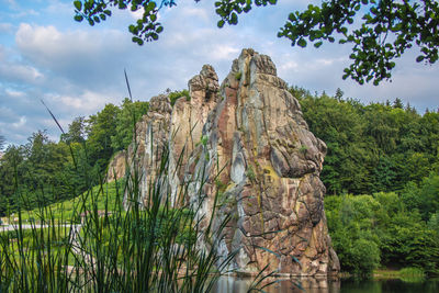 Low angle view of rock formation amidst trees against sky