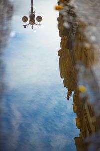 Low angle view of cross amidst buildings against sky