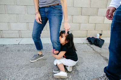 A shy toddler girl grabs tightly onto mother's leg