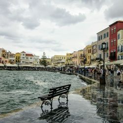 People on wet canal amidst buildings in city against sky