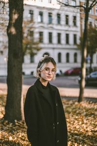 Portrait of young woman standing against trees