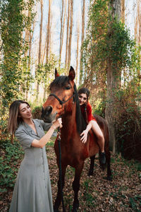 Two women friends chatting and taking a ride with their horse through the countryside