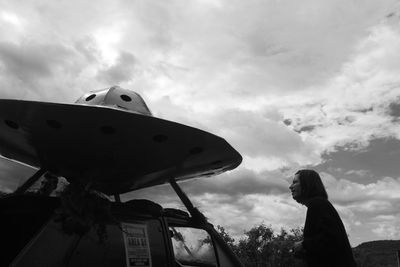 Low angle view of woman looking down against sky