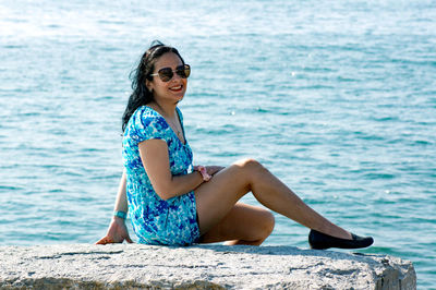 Young woman sitting by sea