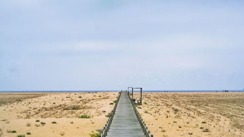 Boardwalk leading towards beach against sky