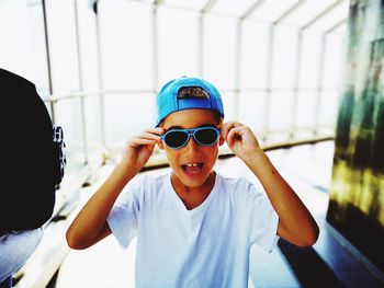 Portrait of boy wearing sunglasses while standing against window