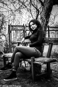 Young woman sitting on bare tree