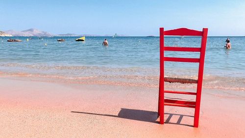 Deck chairs on beach against clear sky