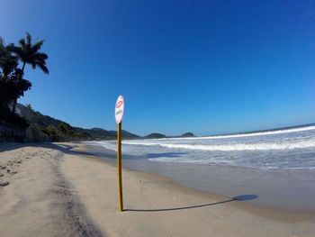 Sign board at beach on sunny day