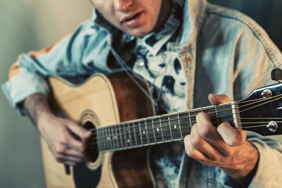 Midsection of man playing guitar