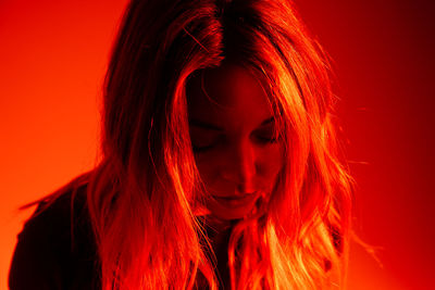 Close-up of depressed young woman against red background