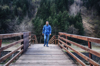 Full length of man on footbridge in forest