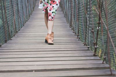 Low section of woman walking on footbridge