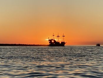 Boat sailing in sea against clear sky during sunset