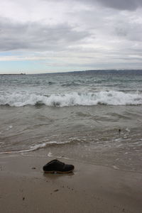 View of calm beach against cloudy sky