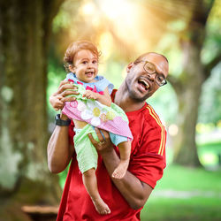 Cheerful father lifting daughter at park