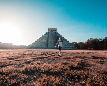 Rear view of woman walking on field against sky