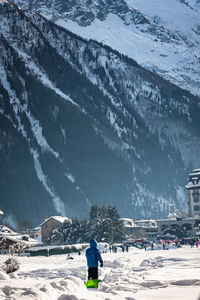 Rear view of man standing on snow covered mountain