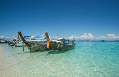 Fishing boat in sea against blue sky