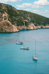 Sailboat sailing on sea against mountain