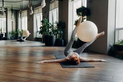 Full length of woman exercising with ball while lying down at gym