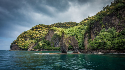 Scenic view of sea by mountain against sky