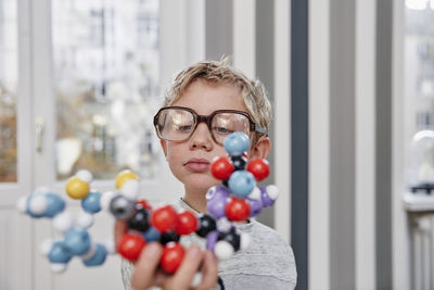 Boy wearing oversized glasses looking at molecular model