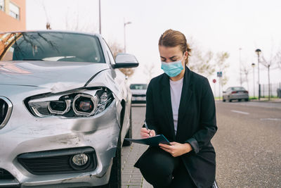 Full length of a woman holding camera while standing in car