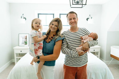 Straight on portrait of a family of four in a modern bedroom