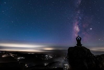 Man standing on rock against sky at night