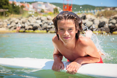 Handsome teenage boy having fun floating on a swim board