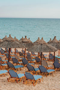 Chairs on beach by sea against sky