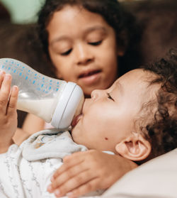 Cute sister feeding brother at home