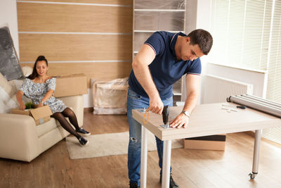 Side view of man using mobile phone while sitting at home