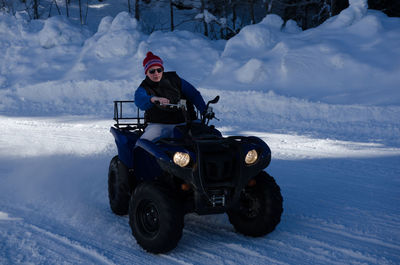 Man driving quadbike on snow covered field