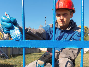 Portrait of young man standing against fence