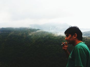 Man smoking cigarette against mountain