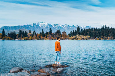 Rear view of man standing on snowcapped mountain against sky