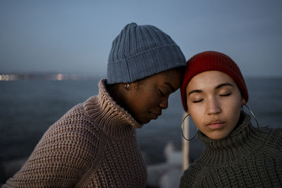 Woman leaning on friend head while standing against sea