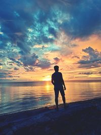 Silhouette man standing on beach against sky during sunset
