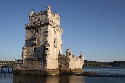 Low angle view of torre de belemm tower by tagus river against clear sky